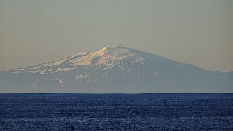 Vulkan, leicht schneebedeckt vom Wasser aus. Abendstimmung.