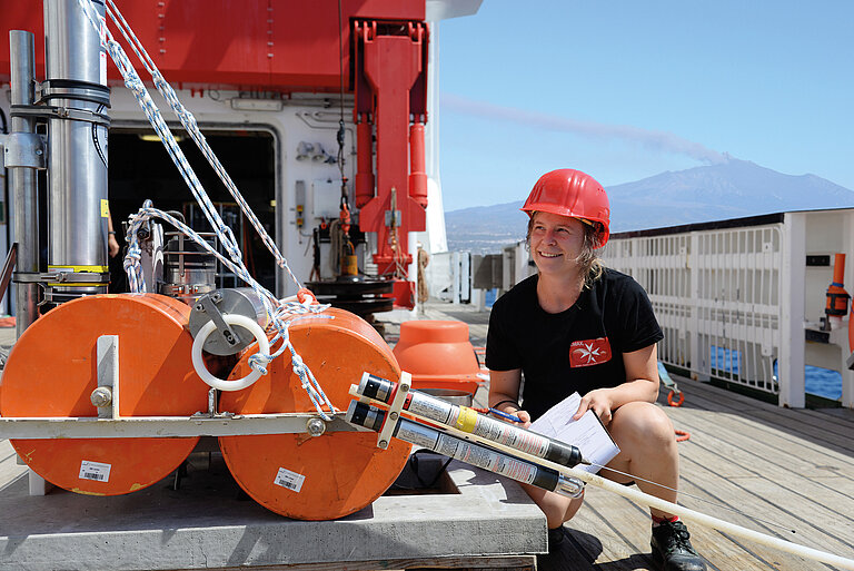 Forscherin mit Ozeanbodenseismometer an Bord eines Forschungsschiffs