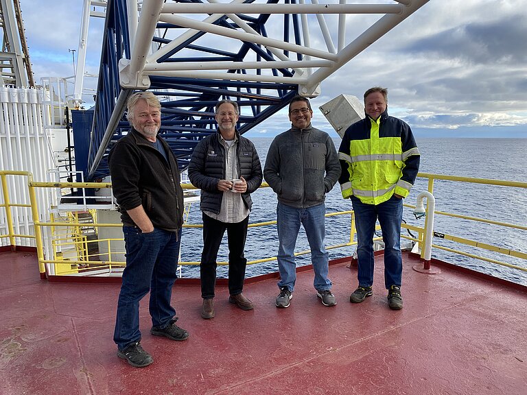 Vier Männer stehen an Bord eines Bohrschiffes.