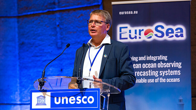 Ein Mann hält einen Vortrag auf einer Bühne.