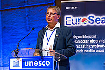 Ein Mann hält einen Vortrag auf einer Bühne.