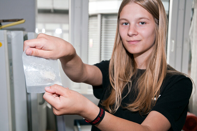 Die 18-jährige Mayla Rens-Kiefel zeigt eine für weitere Analysen zerkleinerte Probe Vulkangesteins. Foto: J. Steffen, GEOMAR