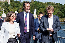 Eine Frau und zwei Männer gehen einen Schiffsanleger entlang