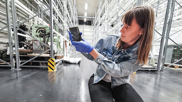 Dr Ulrike Heine with one of the glass negatives of the German Atlantic Expedition in the depot of the German Maritime Museum.