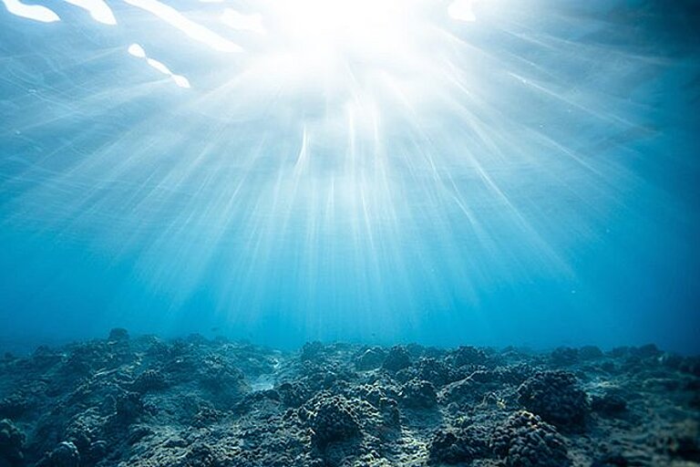 Blick unter Wasser gegen die Meeresoberfläche mit Sonnenstrahlen