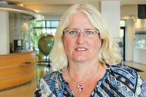 Eine blonde Frau schaut lächelnd in die Kamera