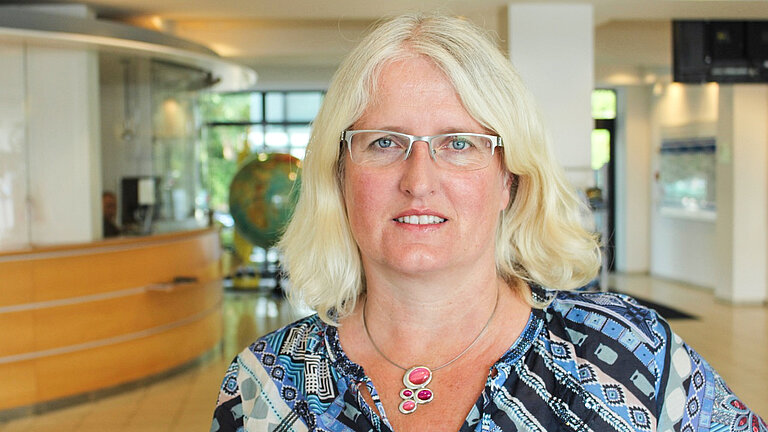 Eine blonde Frau schaut lächelnd in die Kamera