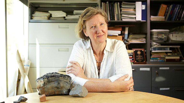 Eine Frau an einem Schreibtisch lächelt in die Kamera