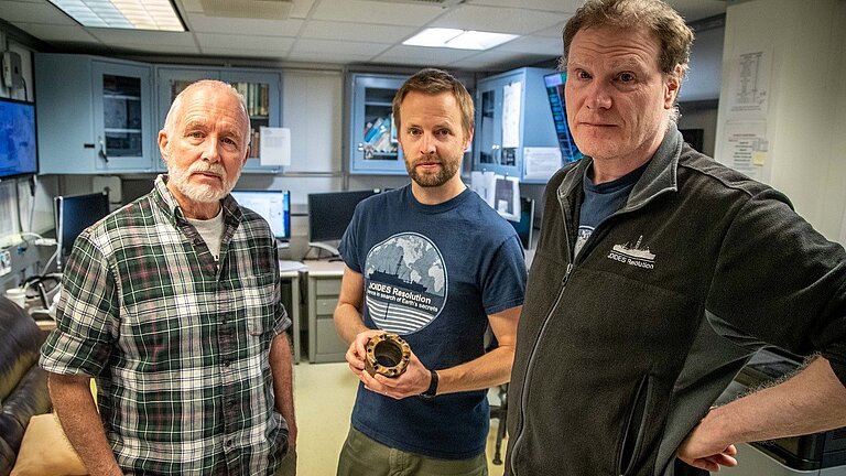 Drei Männer mit einem Stück Rohr