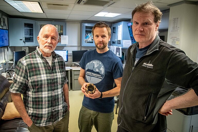 Three men with a piece of pipe