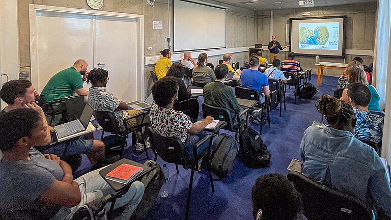 Studierende verschiedener Hautfarbe sehen die Präsentation eines Professors