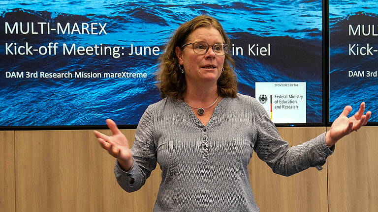 Eine Frau steht vor einer Leinwand und spricht