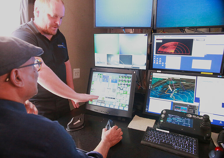 Zwei Männer schauen auf eine Vielzahl von Monitoren