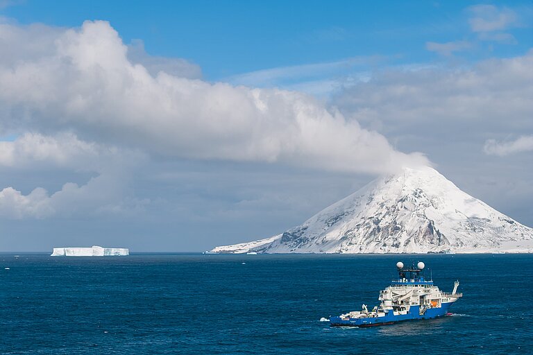 Forschungsschiff Falkor vor einem Vulkan