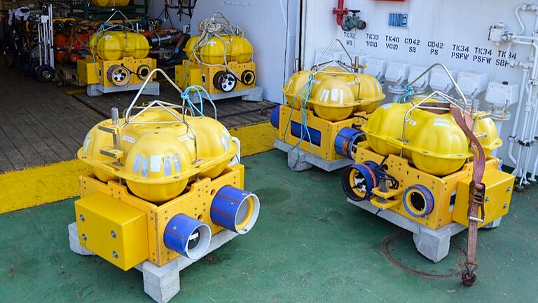 Fünf gelbe kastenförmige Messgeräte stehen auf dem Deck eines Forschungsschiffes