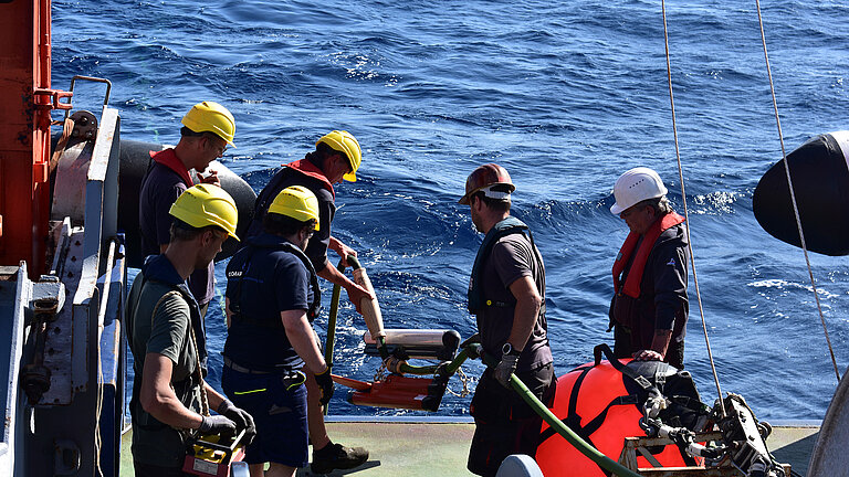 Crew auf dem hinteren Schiffsteil setzt ein Gerät aus