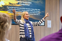 Eine blonde Frau hält begeistert eine Präsentation in einem Konferenzraum