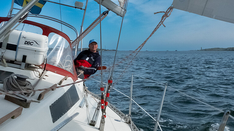 Ein Mann auf einem schräg geneigten Segelboot