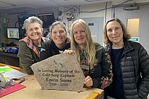 Vier Forscher:innen stehen an einem Tisch und präsentieren den Gedenkstein für Professor Dr. Erwin Suess