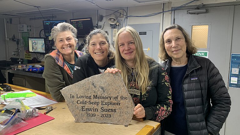 Four researchers stand at a table and present the memorial stone for Professor Dr Erwin Suess.