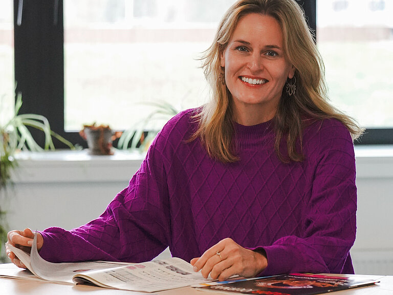 Eine Frau sitzt an einem Tisch und lächelt in die Kamera