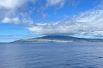 Eine Insel im Meer, das Meer ist sehr blau und der Himmel auch