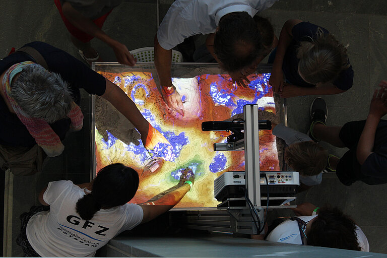 In der Augmented Reality Sandbox des GFZ Potsdam werden Landschaften aus Sand in Echtzeit kartiert und mit simuliertem Wasser gefüllt. Foto: Joachim Dengg, GEOMAR