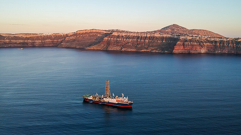 Ein Schiff in der Abendsonne vor einer Küste