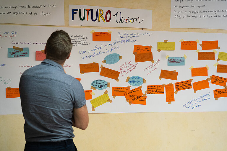 Ein Mann steht vor einer Pinnwand mit bunten Zetteln 