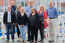 Eine Gruppe Menschen schaut lächelnd in die Kamera