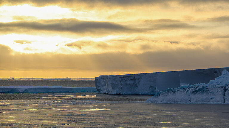 Eisberge auf dem Meer in goldenem Sonnenlicht
