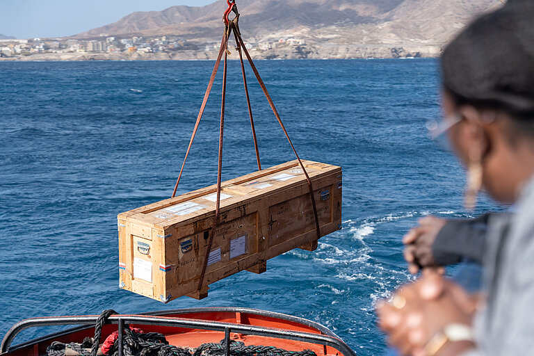 Eine Kiste wird an Bord eines Schiffs geladen