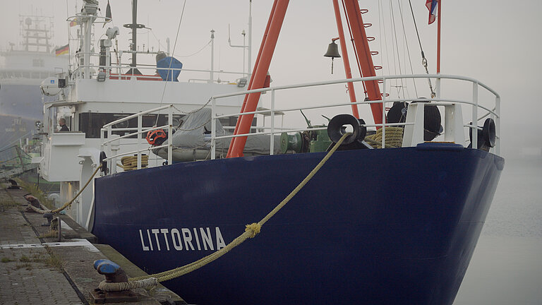 Ein Schiff liegt im Morgennebel an der Pier. 