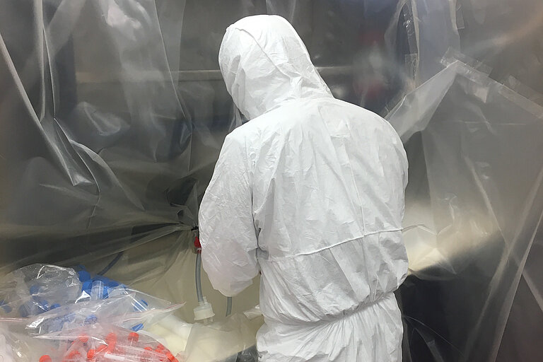 Ship's laboratory of the RRS James Clark Ross with a scientist in a white protective suit. Photo: Thomas Browning. 