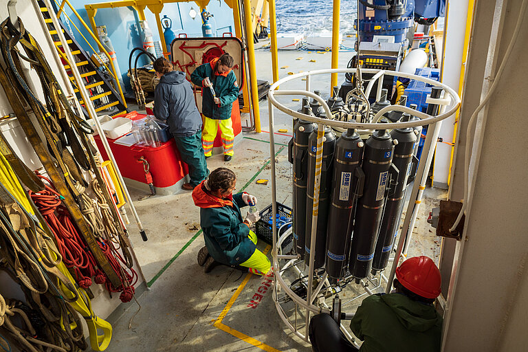 Forschende mit Kranzwasserschöpfer an Bord eines Forschungsschiffes