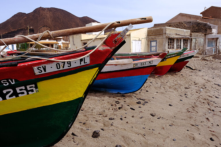 A bunch of painted wooden fishing boats lying on the beach
