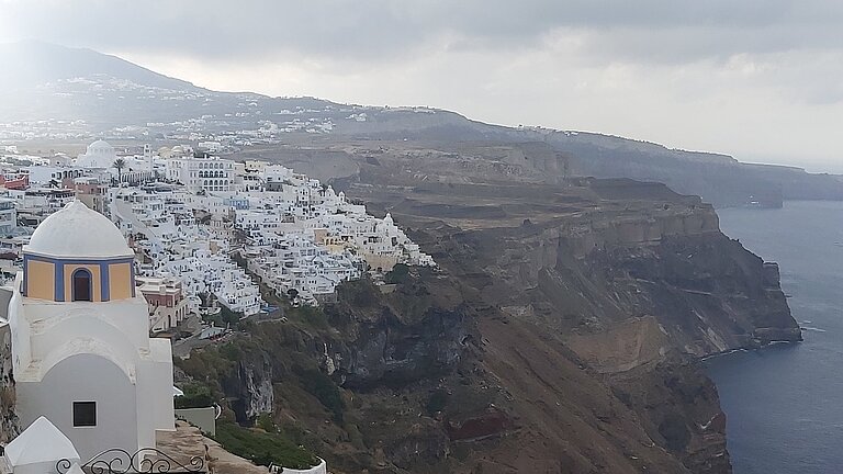 Steile Hänge fallen zum Meer ab, oben auf der Kante sind viele weiße Häuser dicht an dicht gebaut
