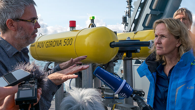 An Bord eines Schiffes stehen Menschen um eine Unterwasserdrohne herum