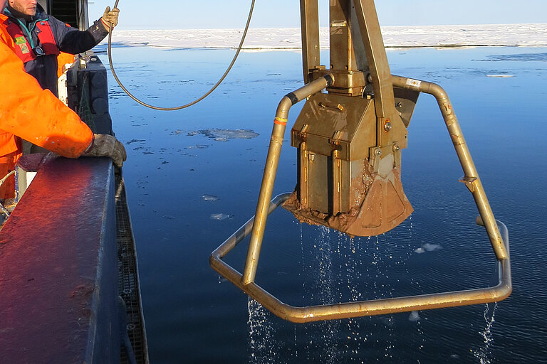 Ein Kastengreifer hängt neben einer Bordwand