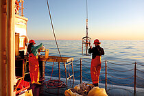 A man and a woman in working clothes stand on the deck of the research vessel ALKOR at dusk. Photo: Jan Dierking/GEOMAR