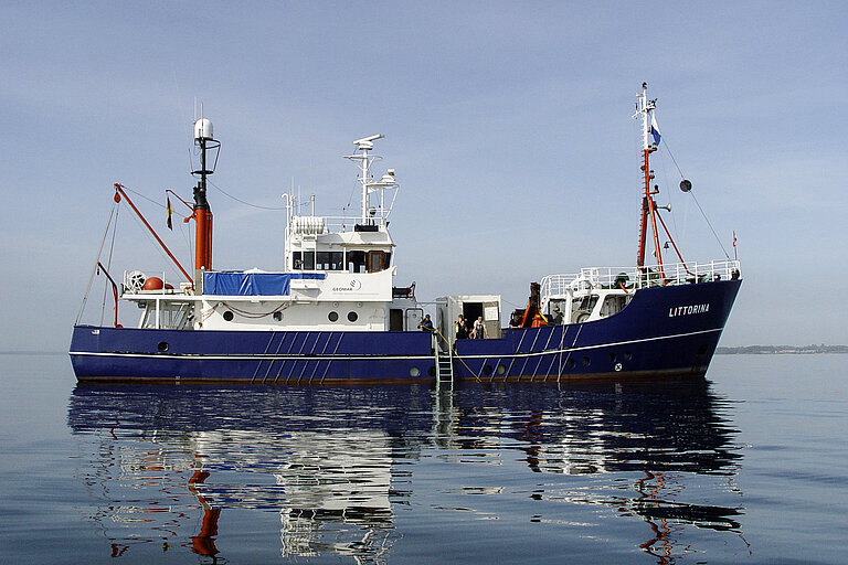 Ein Schiff mit blauem Rumpf auf spiegelglatter See