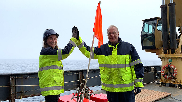 Zwei Personen mit Messgerät an Bord eines Schiffes