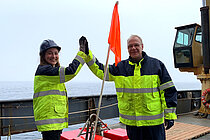 Zwei Personen mit Messgerät an Bord eines Schiffes