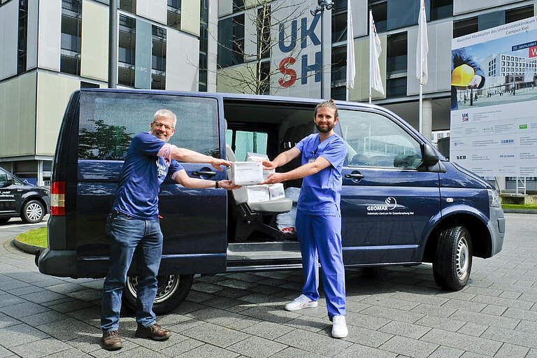 Dr. Andreas Villwock, Pressesprecher des GEOMAR, übergab die Masken an Patrick Ehlers, stv. Teamleitung Pflege in der Klinik für Anästhesiologie. Foto: Maximilian Hermsen, UKSH.