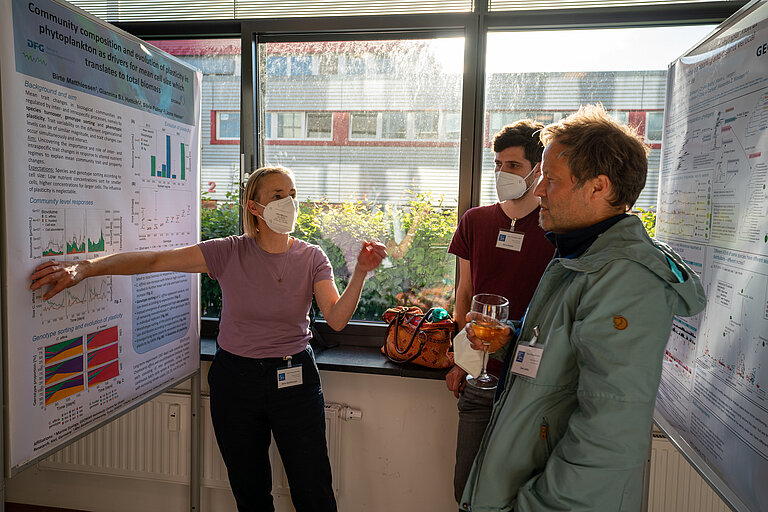 Wissenschaftlerin erklärt ihre Forschungsergebnisse anhand eines wissenschaftlichen Posters.