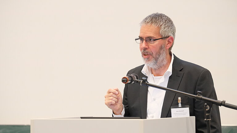 Ein Mann spricht eindringlich an einem Pult mit Mikrophon