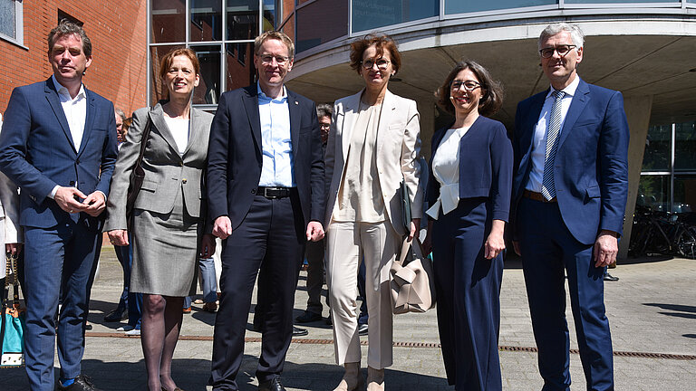 Sechs Männer und Frauen vor einem Gebäude