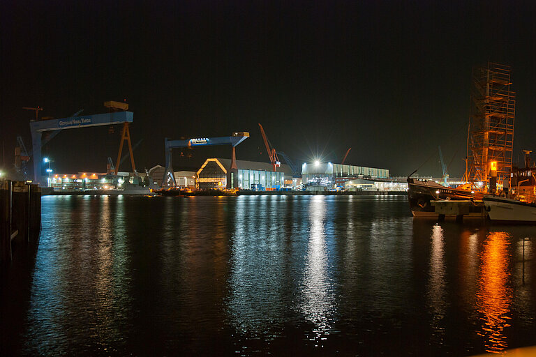 Blick über die Kieler Innenförde bei Nacht. Zahlreiche Lampen erhellen das Wasser.
