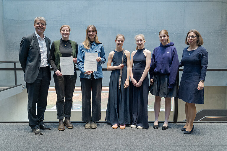 Sieben Personen stehen nebeneinander und lächeln in die Kamera.