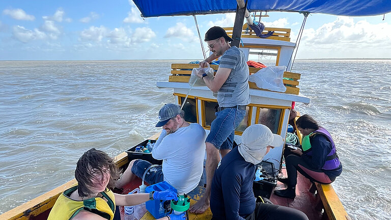 Forschende auf einem kleinen Boot unter einem blauen Sonnensegel
